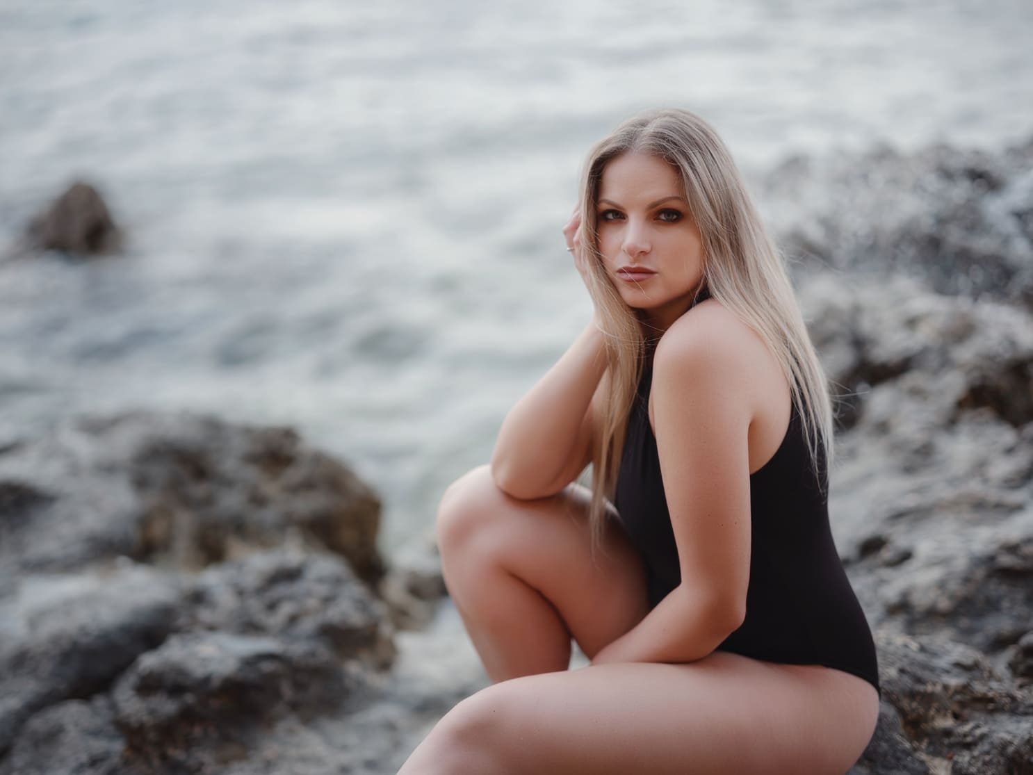 Modelo femenino en un bañador en las rocas de la playa